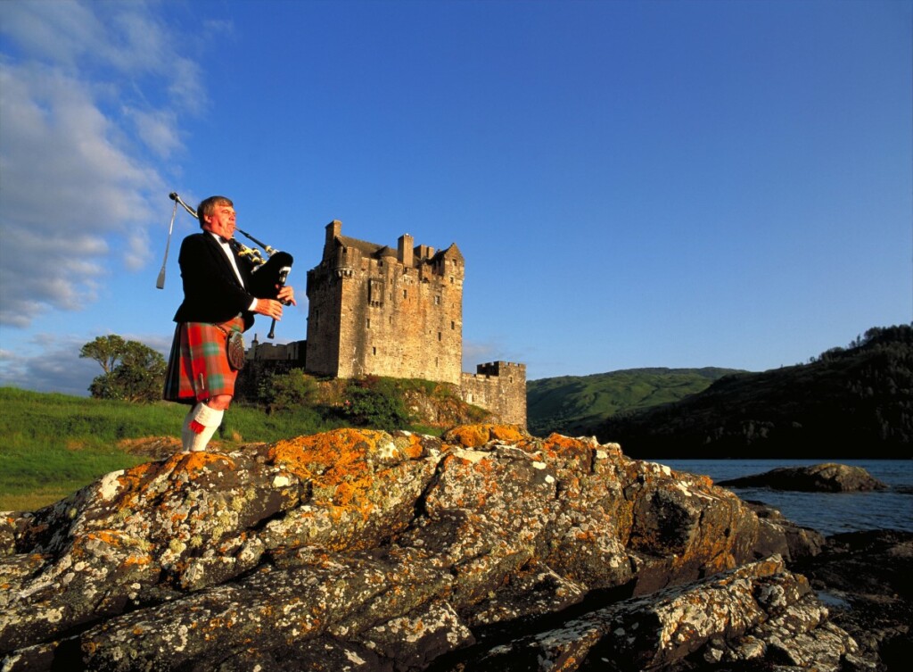 スコットランドのアイリーン・ドナン城をバックにするバグパイプの奏者