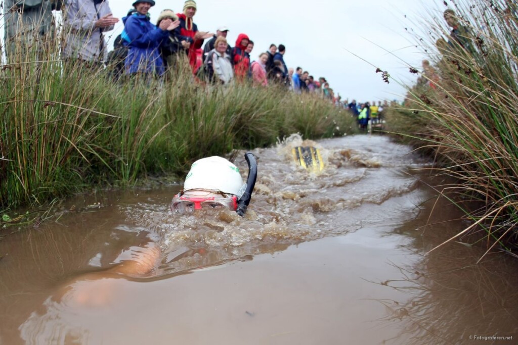 泥の川をシュノーケルで泳ぐレース祭りの参加者
