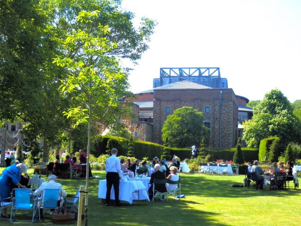 マナーハウスの庭でオペラ上演前にピクニックを楽しむ人々の姿