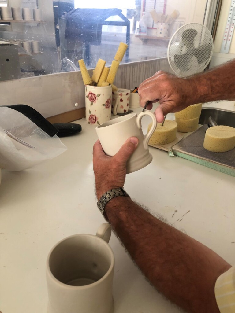 型から取り出したマグカップをナイフとスポンジで成型する作業