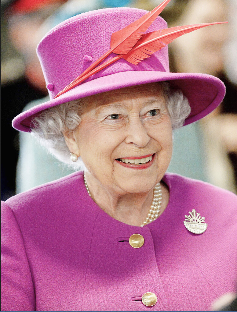 パープルの洋服にパープルの帽子をかぶったエリザベス女王