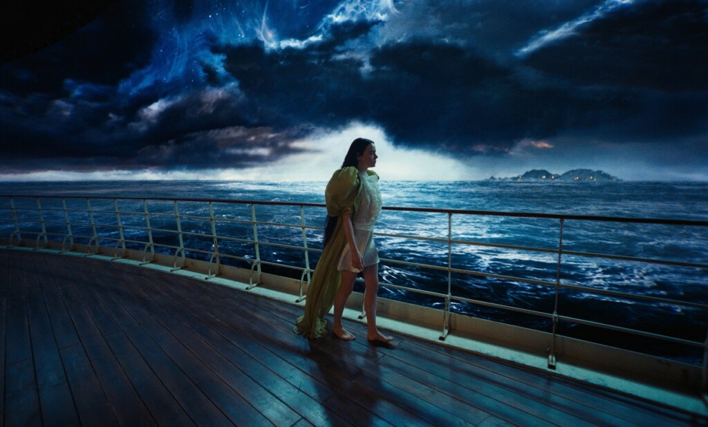 薄暗闇の空と海を背景に、船の上を歩くベラ